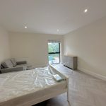 Minimalist bedroom with bed, sofa, window view.