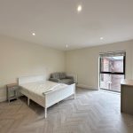 Modern bedroom with bed, sofa, and large window.