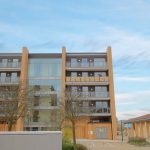 Modern apartment building with glass balconies and trees