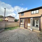 Brick house with paved backyard and conservatory.