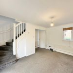 Carpeted room with staircase and window.