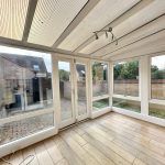 Bright conservatory with wooden flooring and garden view.