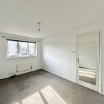 Empty bedroom with carpet and large window.