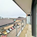 View from balcony overlooking car park and buildings.