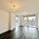 Empty room with wooden floor and large window.