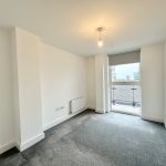 Empty room with large window and grey carpet.