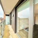 Modern flat balcony view with glass doors.