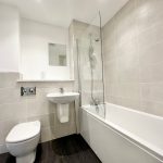 Modern bathroom with tiled walls and white fixtures.