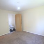 Empty room with en-suite bathroom and carpeted floor.