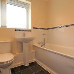 Modern bathroom with toilet, sink, and bathtub.