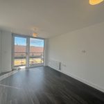 Empty bright room with wooden floor and large windows.
