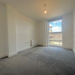 Empty room with grey carpet and large window.