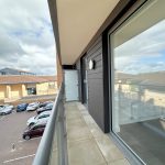 Balcony view of car park and building.
