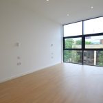 Modern empty room with large window and wooden floor.