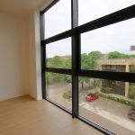 Empty room with large window view of buildings.