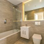 Modern bathroom with shower and illuminated mirror.