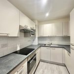 Modern kitchen with white cabinets and appliances.