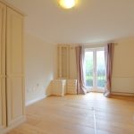 Bright bedroom with wooden floor and French doors.