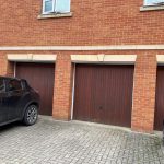 Row of brick garages with parked cars.
