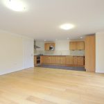 Spacious open-plan kitchen with wooden flooring.