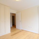 Empty room with wooden flooring and wardrobes