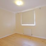 Empty room with wood flooring and closed blinds.