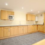 Modern kitchen with wooden cabinets and tiled floor.