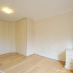 Empty room with wooden floor and built-in wardrobes.