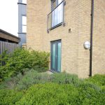 Brick building with garden and glass doors.