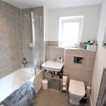 Modern bathroom with bathtub and grey tiles.