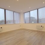 Empty office space with large windows and blinds.