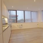 Modern empty kitchen with large windows and blinds.