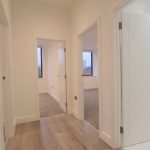 Modern hallway with white doors and wooden floor.