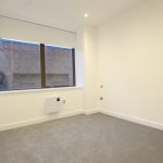 Empty room with large window and grey carpet.