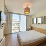 Modern bedroom with large window and TV.