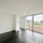Empty room with large windows and wooden floor.