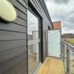 Modern balcony with glass railing and city view.
