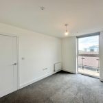 Empty room with large window and grey carpet.