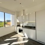 Modern kitchen with large window and white cabinets.