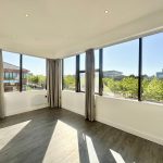 Bright empty room with large windows and wood floors.