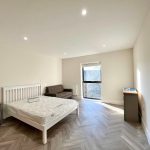 Minimalist bedroom with bed, sofa, and window.
