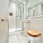 Modern bathroom with shower and wooden toilet seat.