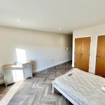 Minimalist bedroom with wooden flooring and furniture.