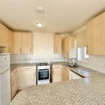 Modern kitchen with granite countertops and wooden cabinets.