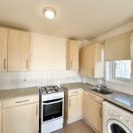 Modern kitchen with appliances and light wood cabinets.