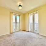 Empty room with carpet and balcony doors.