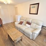 Living room with sofa, dining table, and wooden floor.