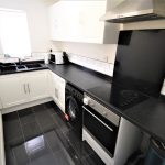 Modern kitchen with black countertops and white cabinets.