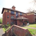 Modern brick apartment building with lush surroundings.