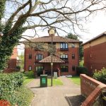 Red brick apartment buildings with trees and pathway.